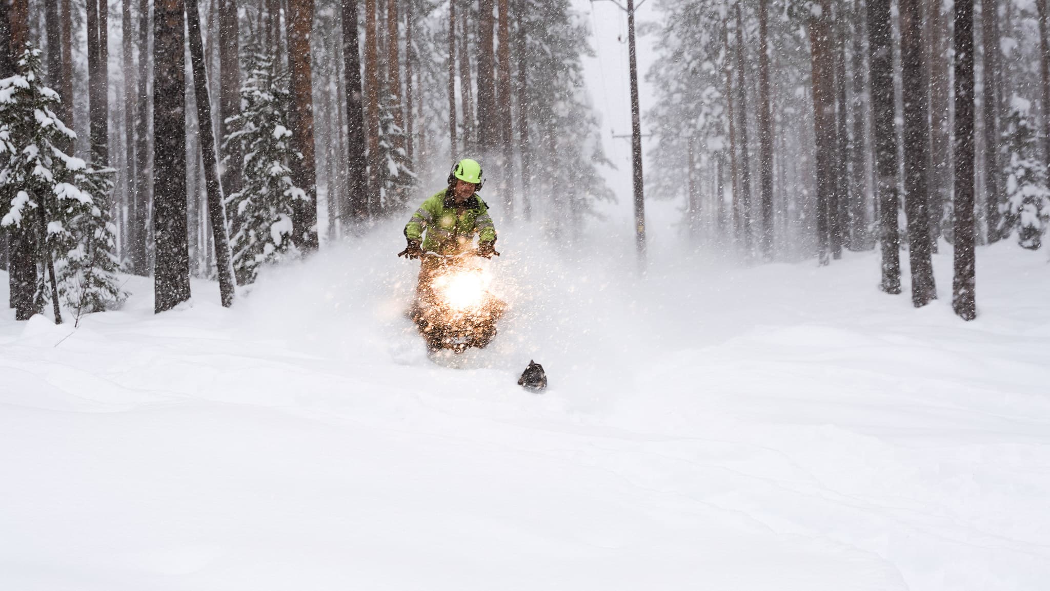 Man i gula varselkläder kör skoter längs en igensnöad kraftledningsgata. Elnätsbolaget BTEA jobbar i alla väderförhållanden.